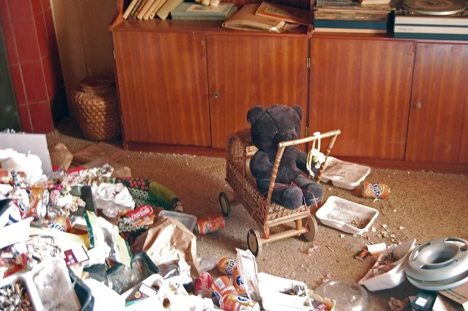 An armchair and belongings in an unoccupied home, from the Sporen archive selection.