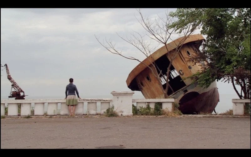 A person stands beside a stranded ship on a waterfront in The Lost Colony.